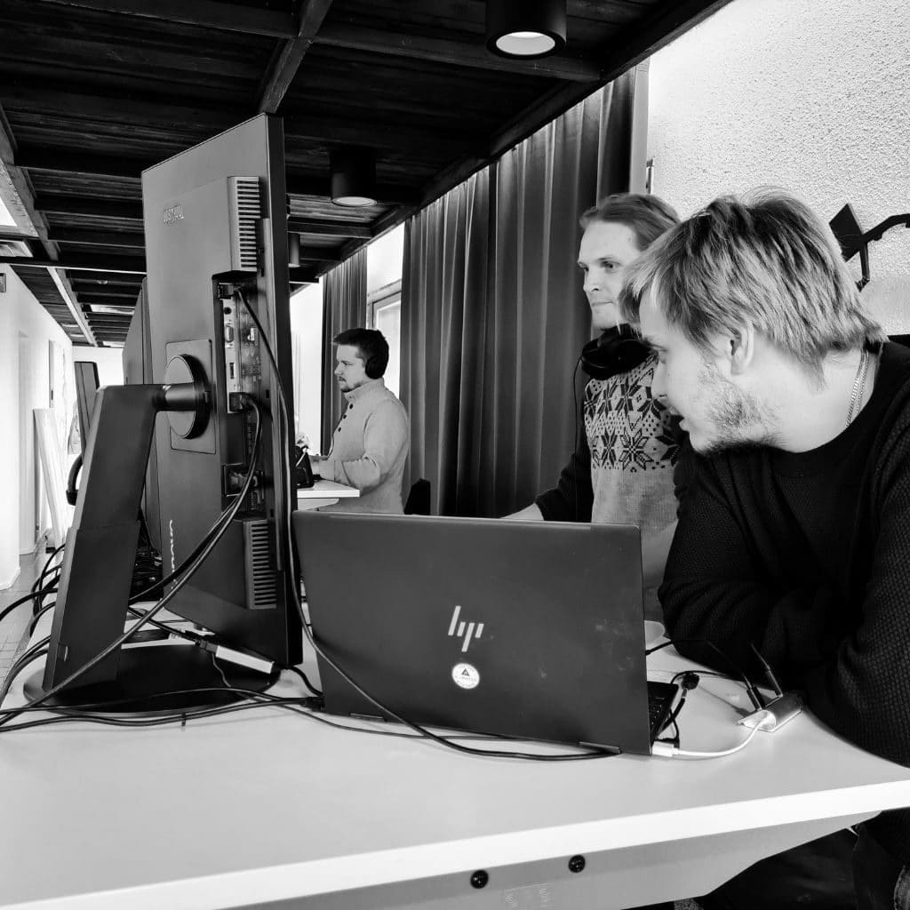 Antti, Kai ja Aleksi tekevät tietokoneen edessä töitä. Mustavalkoinen kuva.